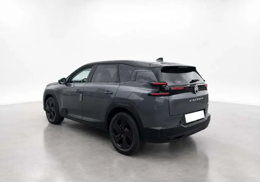 Vue 3/4 arrière droit du Citroën C5 Aircross gris foncé avec toit noir et jantes noires dans un studio blanc.
