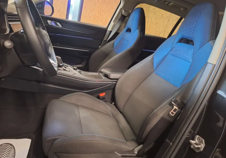 Vue intérieure côté conducteur du Lynk & Co 01 2023, sièges tissu noir et bleu avec console centrale moderne.