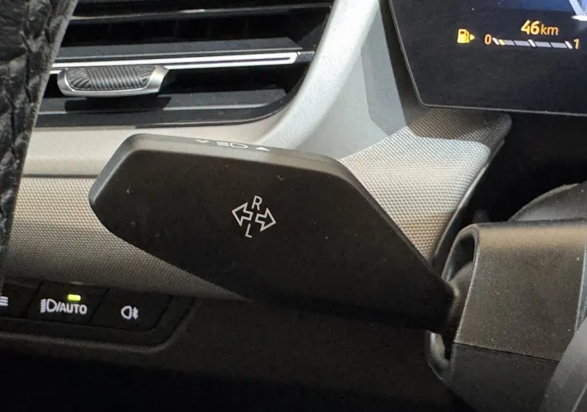 Gros plan sur la commande de réglage des rétroviseurs à gauche du volant dans l’habitacle gris clair du BMW X1 2024.