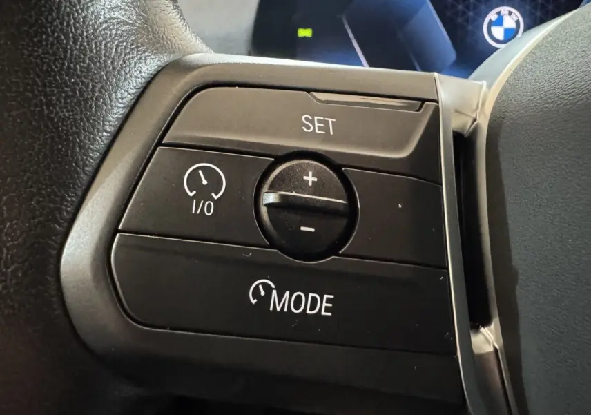 Gros plan sur les commandes de régulateur de vitesse au volant cuir du BMW X1 gris foncé 2024.