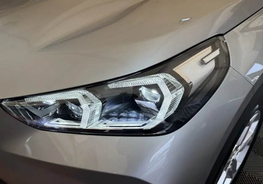 Gros plan sur le phare avant droit LED du BMW X1 sDrive20i gris foncé, soulignant ses lignes modernes et précises.