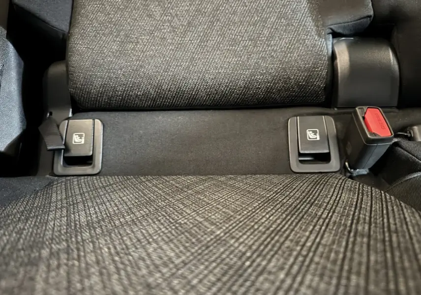 Gros plan sur la banquette arrière grise du BMW X1 2024, montrant les fixations Isofix et la boucle de ceinture.