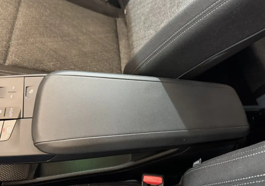 Gros plan sur l'accoudoir central noir et la console entre les sièges avant du BMW X1 gris foncé 2024.