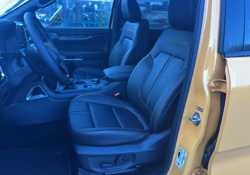 Vue intérieure côté conducteur du Ford Ranger Cyber orange 2026, sièges cuir noirs Wildtrak avec surpiqûres contrastées.