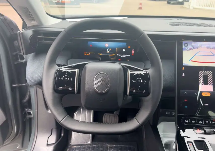 Vue intérieure centrée sur le volant cuir multifonctions du Citroën C5 Aircross Hybrid 145 Plus PK Drive, tableau de bord numérique visible.