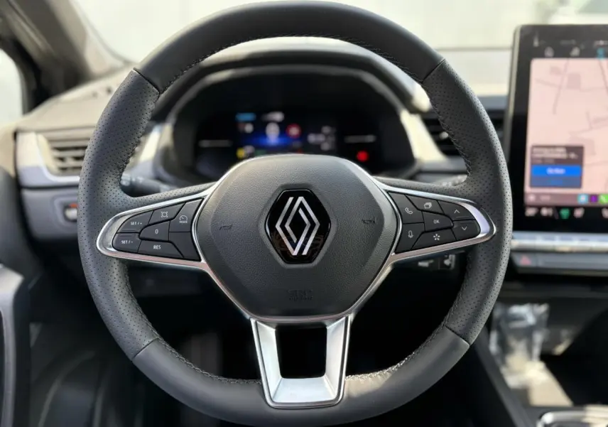 Volant en cuir perforé avec logo Renault au centre, tableau de bord numérique et écran tactile à droite du Renault Captur 2025.
