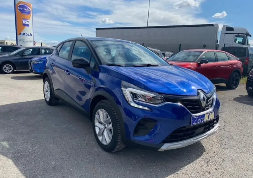 Renault Captur Evolution Mild Hybrid 140 EDC bleu Iron vu en 3/4 avant sur parking extérieur avec plaque Zero KM.