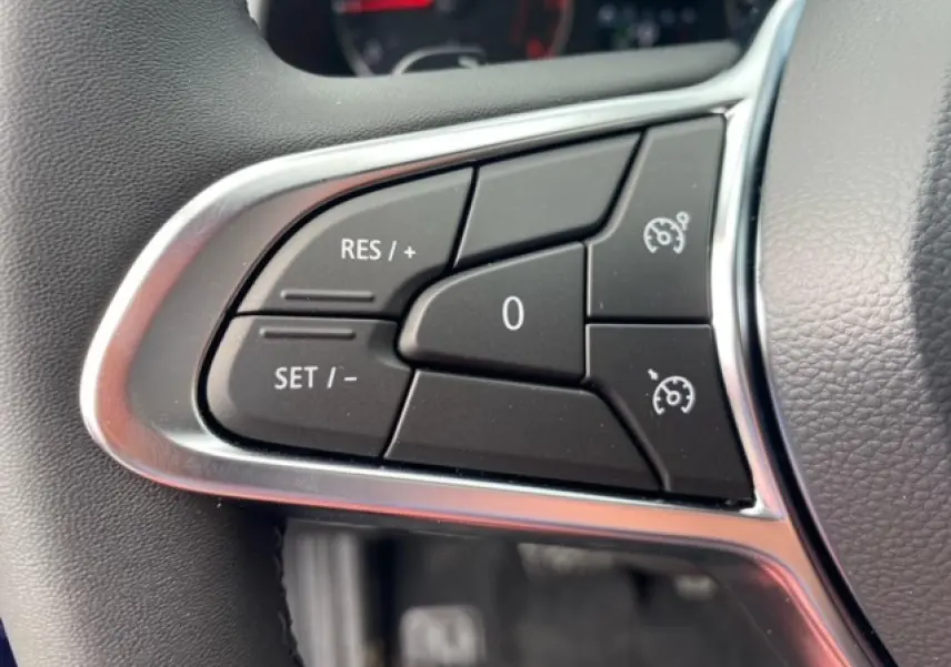 Gros plan sur les commandes du régulateur de vitesse au volant du Renault Captur bleu Evolution Mild Hybrid 2023.