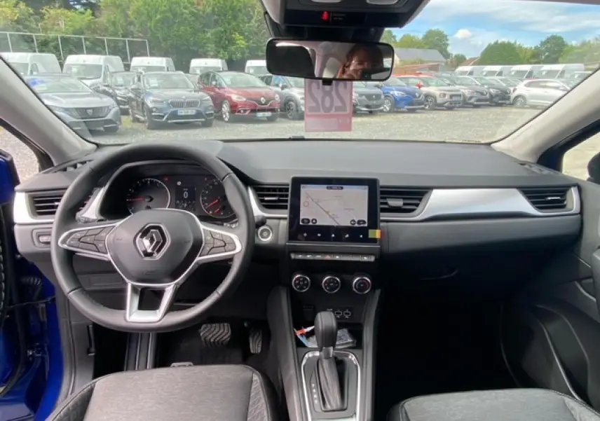 Vue intérieure du tableau de bord du Renault Captur bleu 2023 avec écran tactile 9,3 pouces et volant multifonction.