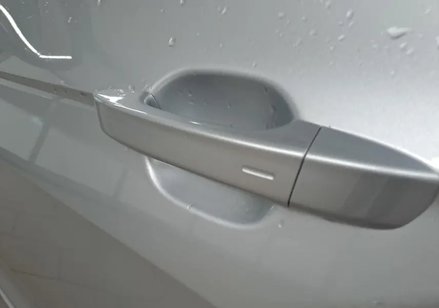 Poignée de porte côté gauche du Volkswagen T-Cross 2025 R-Line Edition en Reflet d'argent avec gouttes d'eau visibles.