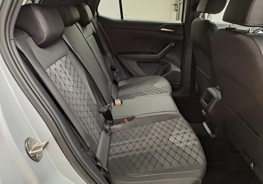 Vue intérieure côté gauche des sièges arrière du Volkswagen T-Cross 2025 R-Line Edition avec sellerie tissu noir à motifs.