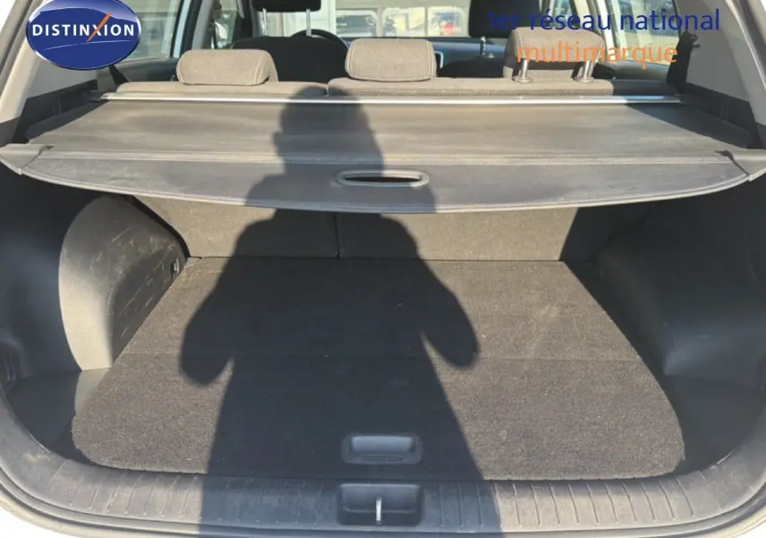 Coffre ouvert d'un KIA Sportage blanc nacré, vue arrière montrant la plage arrière et l'espace de chargement.