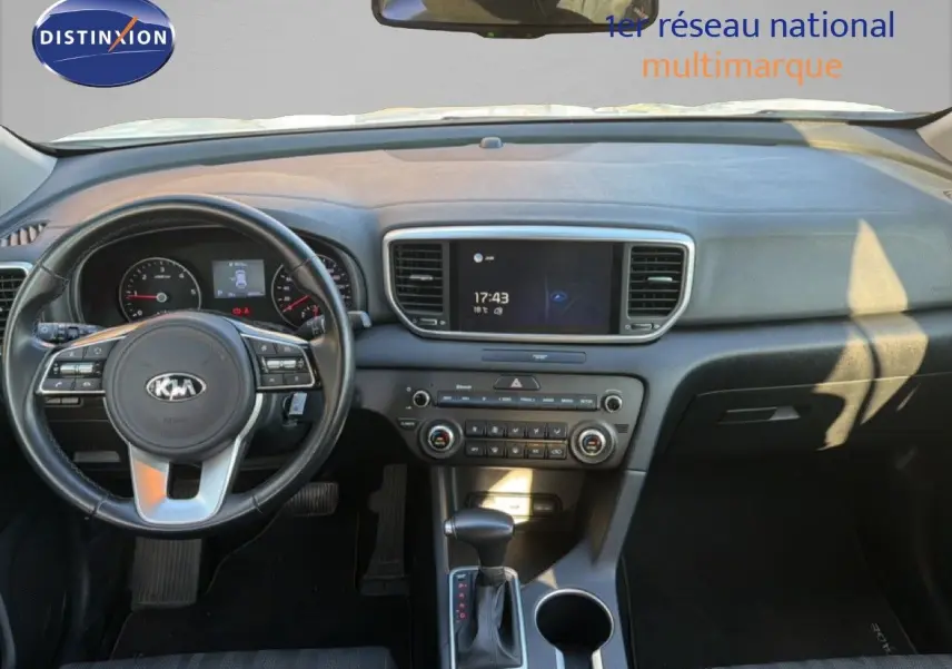 Vue intérieure du tableau de bord du Kia Sportage 2021, volant à gauche, console centrale avec écran tactile et levier de boîte automatique.
