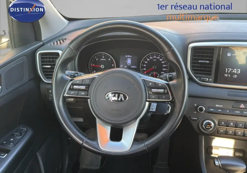 Vue intérieure centrée sur le volant noir du Kia Sportage 2021 avec tableau de bord et écran tactile visibles.