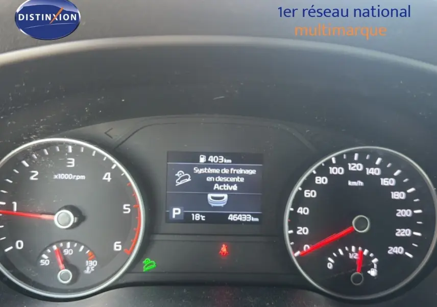 Vue rapprochée du tableau de bord du Kia Sportage blanc nacré 2021, affichant le compteur et l'écran central numérique.