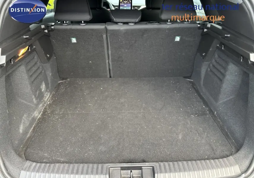 Vue intérieure du coffre spacieux et noir d’un Renault Symbioz blanc nacré, avec sièges arrière et écran tactile visibles.