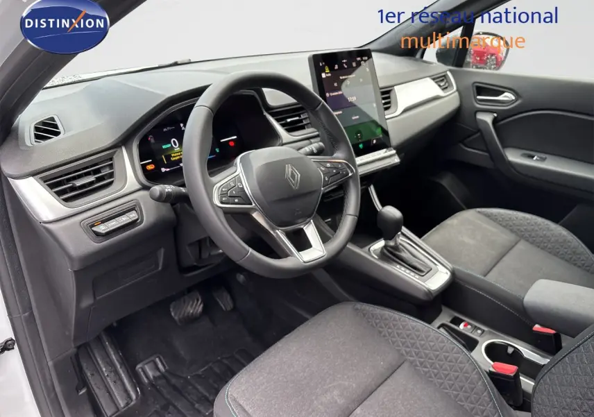 Vue intérieure côté conducteur du Renault Symbioz blanc nacré, mettant en valeur le volant multifonction et la console centrale avec boîte auto.