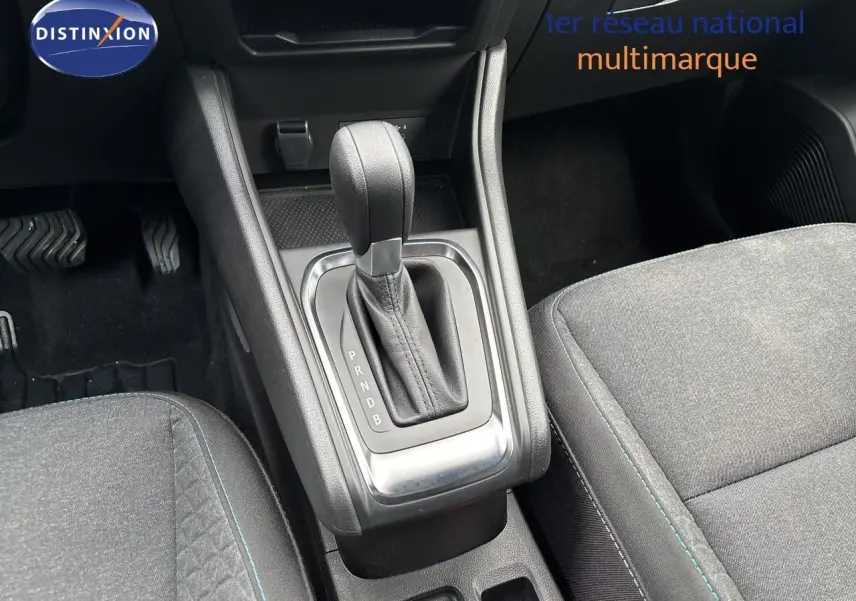 Gros plan sur la console centrale et levier de vitesse automatique d’un Renault Symbioz blanc nacré, sièges tissu gris.