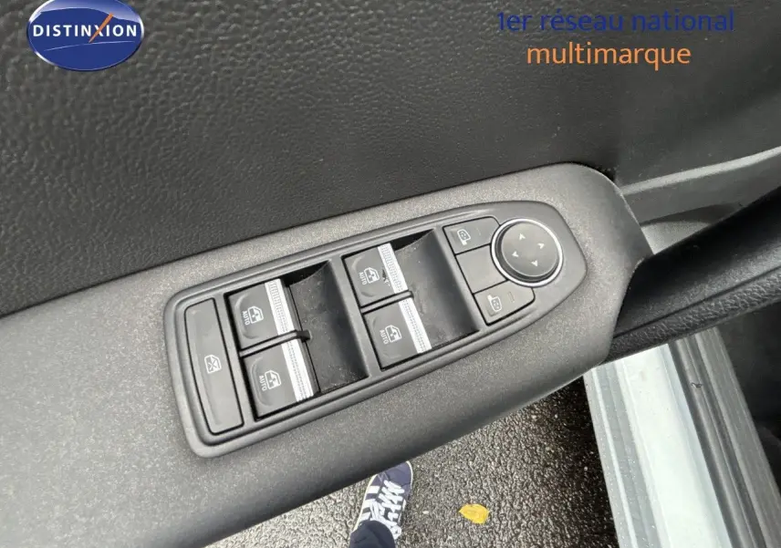 Gros plan sur les commandes de lève-vitres et rétroviseurs sur la portière côté conducteur d’une Renault Symbioz blanc nacré.