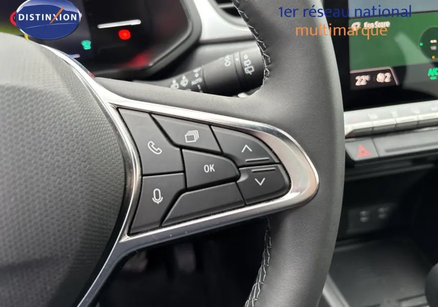 Gros plan sur les commandes au volant à droite du Renault Symbioz blanc nacré, avec tableau de bord numérique en arrière-plan.