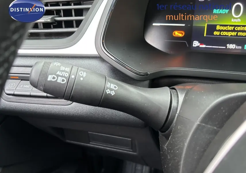 Gros plan sur la commande des phares et clignotants à gauche du volant du Renault Symbioz blanc nacré, tableau de bord numérique visible.