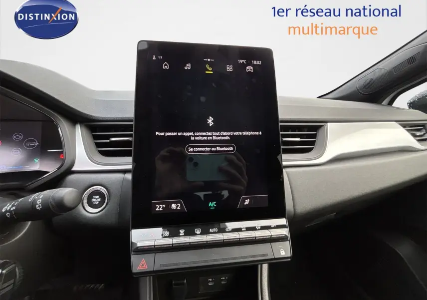 Vue intérieure centrée sur l'écran tactile vertical du tableau de bord de la Renault Symbioz blanc nacré, avec commandes climatisation visibles.