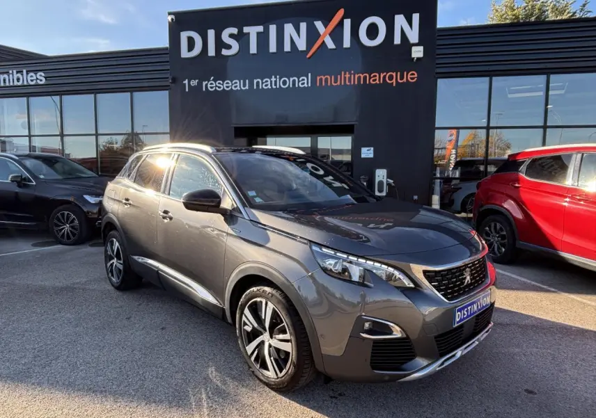 Peugeot 3008 gris métal en 3/4 avant droit, avec jantes alliage et calandre distinctive GT Line devant un showroom Distinxion.