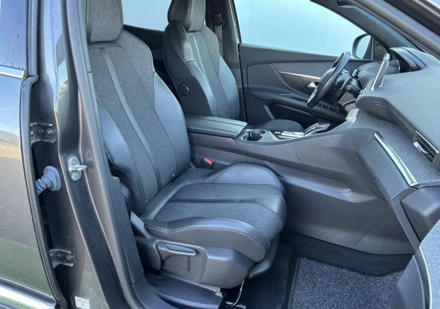 Intérieur côté conducteur du Peugeot 3008 gris métal 2020, sièges en tissu et cuir, tableau de bord moderne visible.