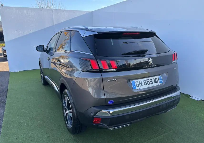 Peugeot 3008 gris métal vue 3/4 arrière droit, feux arrière à trois griffes et toit noir brillant.
