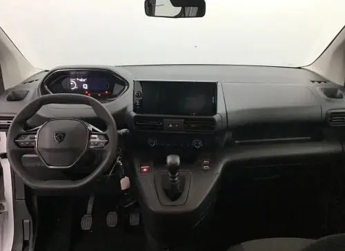 Vue frontale de l'intérieur noir du Peugeot Rifter 2025, avec volant compact, tableau de bord numérique et levier de vitesses manuel.