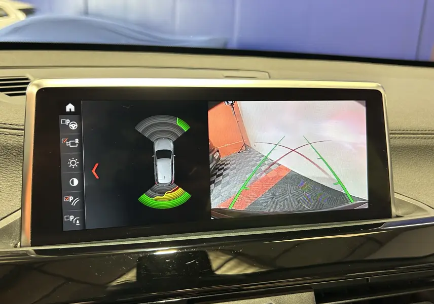 Écran central de BMW X1 noir 2019 montrant la caméra de recul et les capteurs de stationnement actifs.