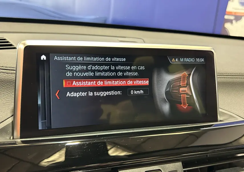 Écran central de la BMW X1 2019 affichant l'assistant de limitation de vitesse, vue intérieure frontale.