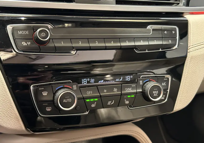 Détail de la console centrale noire du BMW X1 2019 avec commandes climatisation automatique et réglages chauffants.