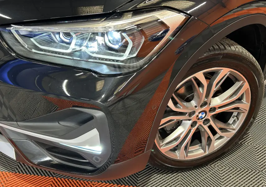 Gros plan sur l'avant droit noir du BMW X1 2019, mettant en valeur le phare LED et la jante alliage.