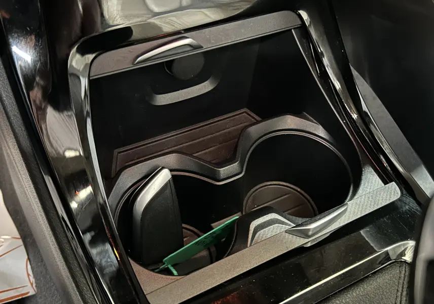 Gros plan sur le porte-gobelets central noir brillant de la BMW X1 sDrive18iA 2019 avec insert en carbone.