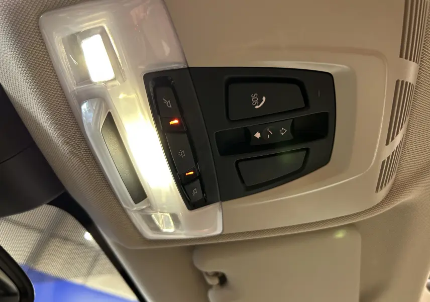 Vue intérieure du plafonnier avec commandes d’éclairage et bouton SOS dans un BMW X1 noir de 2019.