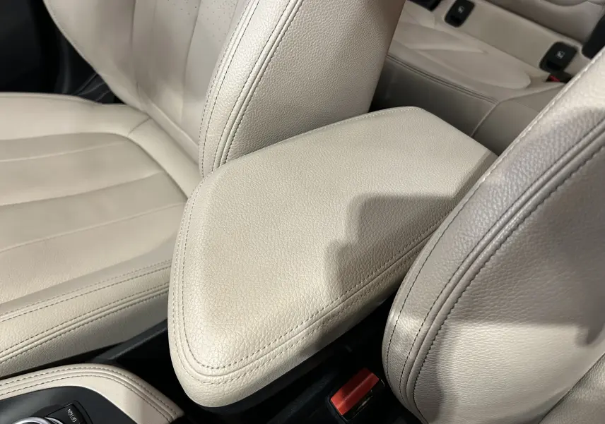 Gros plan sur l'accoudoir central en cuir beige clair à l'intérieur du BMW X1 sDrive18iA 2019.