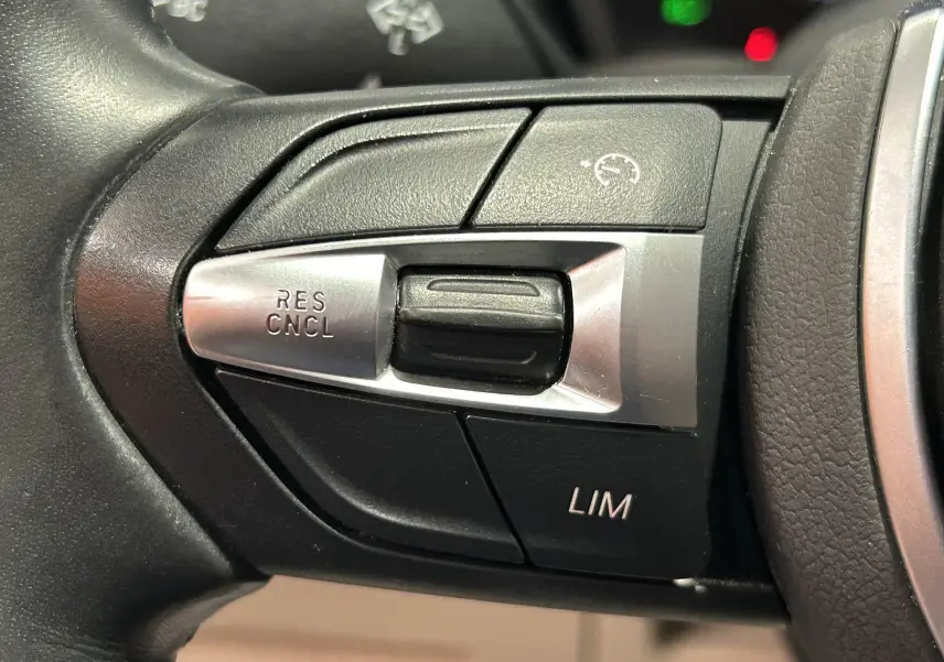 Gros plan sur les commandes de régulateur de vitesse au volant noir du BMW X1 sDrive18iA 2019.