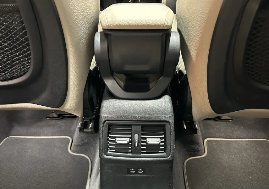 Vue centrée sur la console arrière beige et noire du BMW X1 2019, avec aérateurs et ports USB visibles.