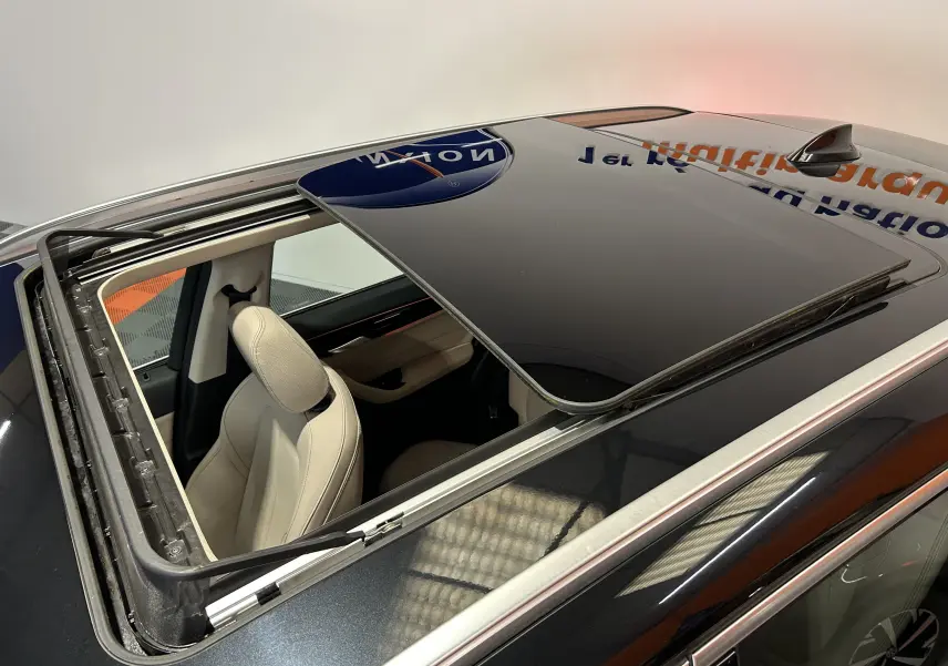 Toit ouvrant ouvert vu de dessus sur BMW X1 noir, montrant l'intérieur beige et les barres de toit argentées.