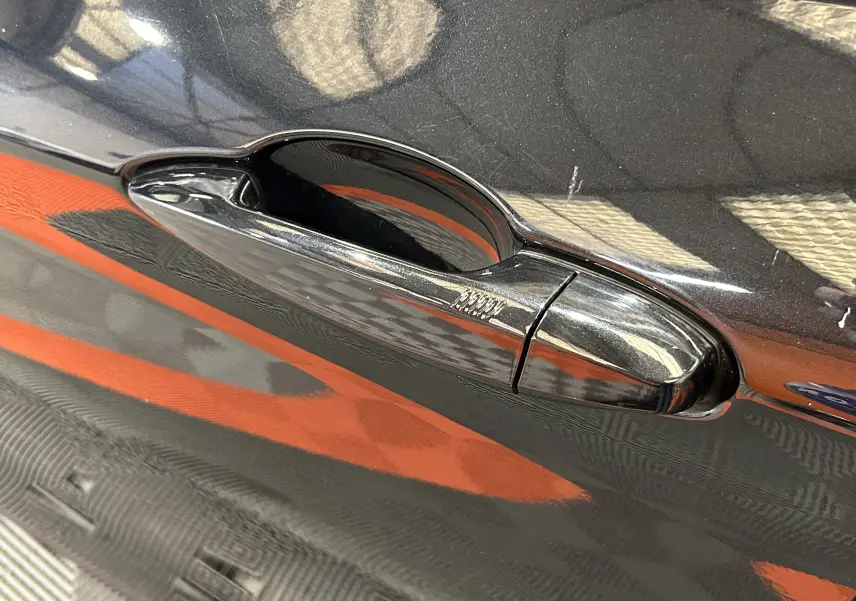 Poignée de porte noire brillante du BMW X1 sDrive18iA 2019, vue en gros plan sur la portière côté droit.