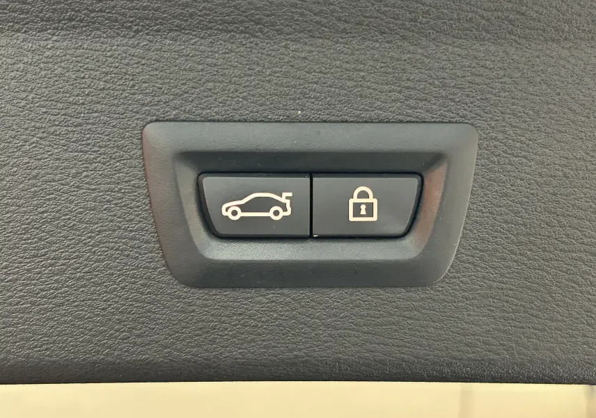 Gros plan sur les boutons d'ouverture du hayon électrique et de verrouillage dans un BMW X1 noir, version xLine.