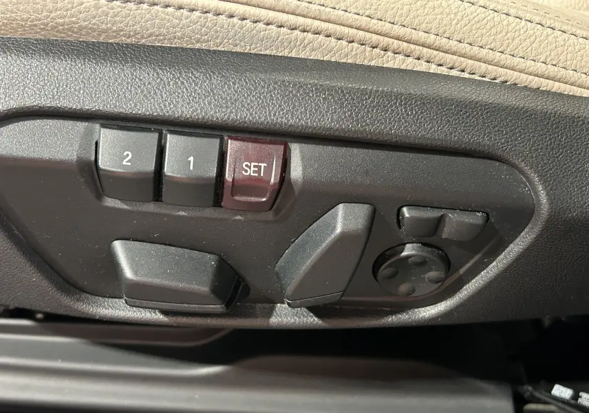 Gros plan sur les commandes de réglage électrique des sièges en cuir beige d'un BMW X1 noir 2019.