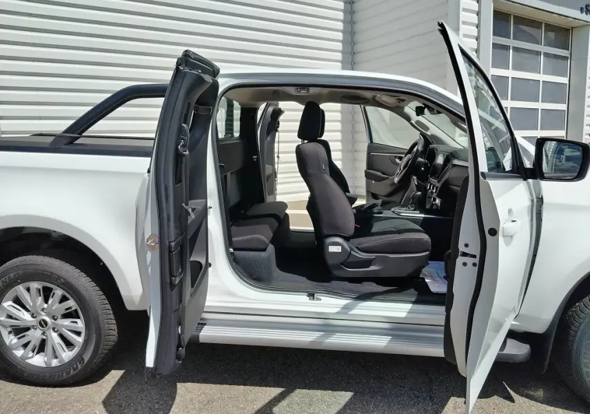 Vue latérale gauche d'un Isuzu D-MAX blanc 2026 avec portes ouvertes, arceau et bac de benne visible.
