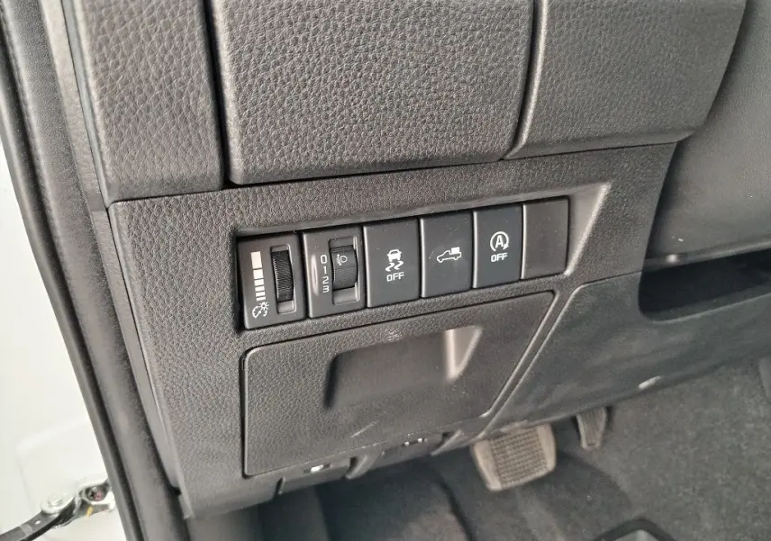 Vue rapprochée des commandes de réglage et d'assistance situées à gauche du volant dans un Isuzu D-MAX blanc 2026.