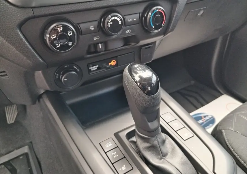 Gros plan sur la console centrale et levier de vitesse automatique du pick-up Isuzu D-MAX 2026, intérieur noir.