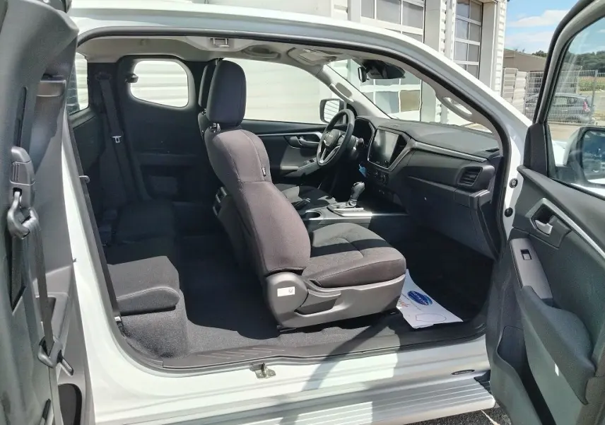 Intérieur du pick-up Isuzu D-MAX blanc vu côté gauche avec sièges noirs et tableau de bord moderne.