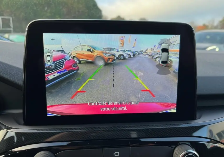 Écran de caméra de recul montrant l'arrière rouge Lucifer du Ford Kuga 1.5 EcoBoost ST-Line en stationnement.