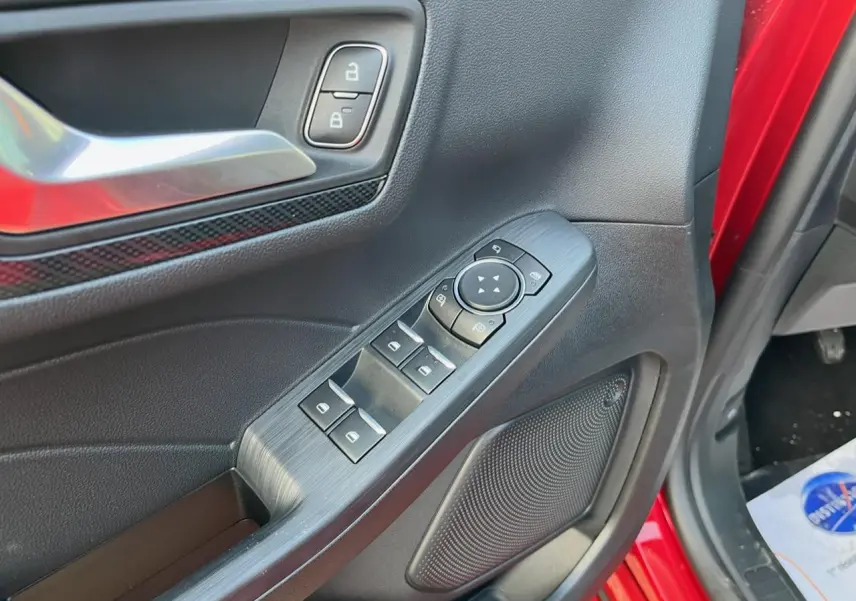 Gros plan sur la porte avant gauche rouge Lucifer du Ford Kuga 2022, montrant les commandes électriques et la poignée intérieure.