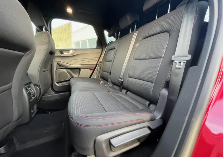 Vue latérale intérieure montrant la banquette arrière noire avec surpiqûres rouges du Ford Kuga rouge Lucifer 2022.